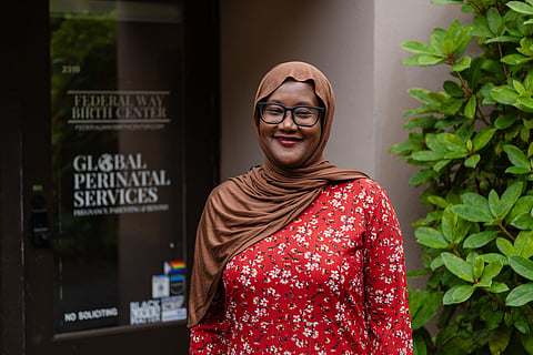Faisa Farole stands in front of an office building and greenery.