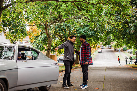 Zia Mohajerjasbi points to a car and speaks with an actor on a film set on a Central District street.