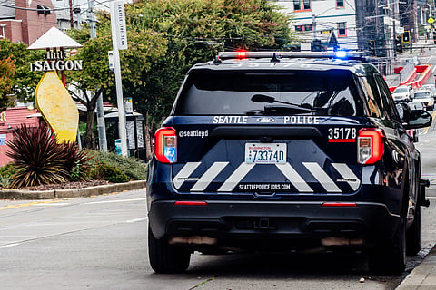 Seattle police car on street by Little Saigon sign.