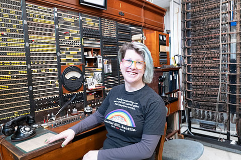 Sarah Autumn next to an old telephone switchboard.