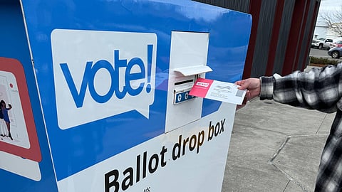 A voter drops off their ballot at a drop box.