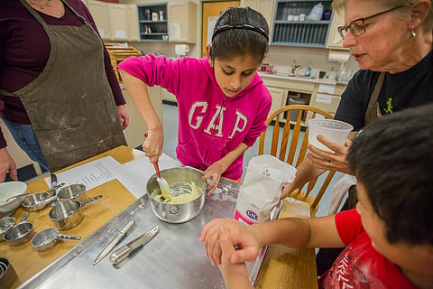 Arushi Mittal, center, mixes softened butter with sugar, as teachers and fellow student, G, right, assist, during the Washington State Department of Services for the Blind's baking workshop in Seattle, Washington, on Dec. 14, 2019. (Photo: Carolyn Bick)