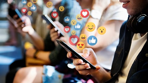Photo depicting people watching video or searching social media on smart phones with a cloud of likes, hearts, and emojis rising from the devices.