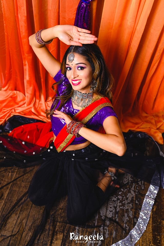 Priyanka Jain Vora poses and smiles at the camera, situated slightly above her