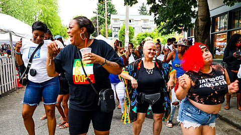 A crowd enjoys a Beatwalk event, dancing in the street while smiling