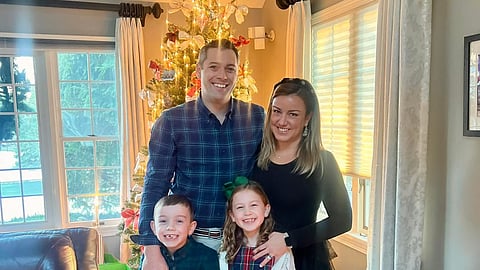 A family photo of four in front of a Christmas Tree. 
