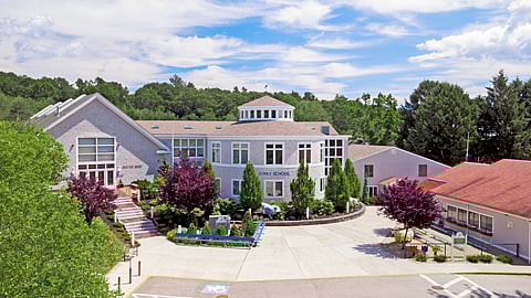 Inly School campus with tan colored buildings with colorful trees around a courtyard. 