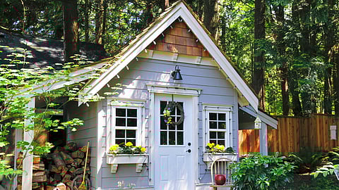 Small backyard cottage with window boxes and lush greenery surrounding it. Scituate Select Board discusses the impact of short-term rentals in Accessory Dwelling Units (ADUs).