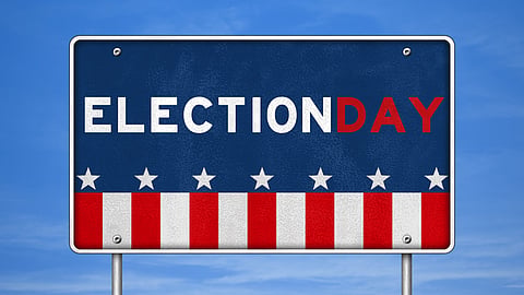 Blue sky background with a red white and blue road sign that says Election Day