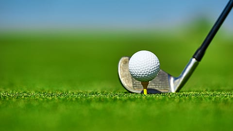 golf green with up close image of golf ball on tee with a driver