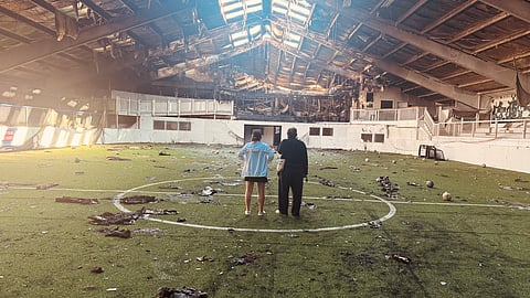Liz Lima and her father inspect damage caused by the fire at South Shore Sports Center. 