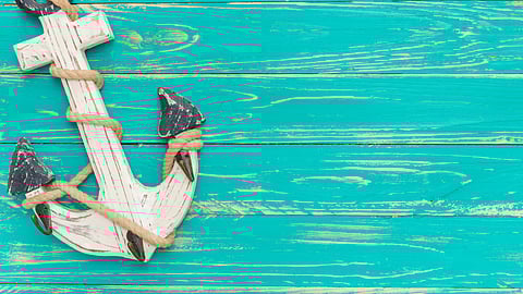 turquoise wooden background with an anchor on top