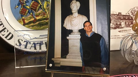 a young man stands next to a stone bust of Abraham Lincoln 
