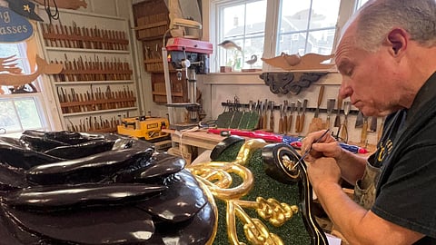 a man works on painting a black rose sign