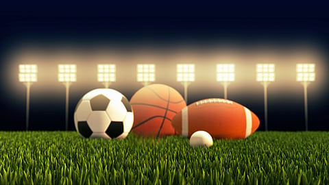 soccer ball, basketball ball, football on a turf field with lights over it
