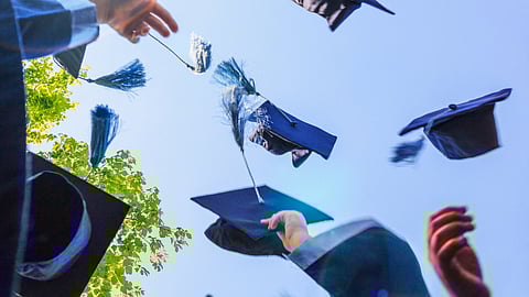 Hands throw blue graduation caps up against a blue sky. Hanover Public Schools leaders outline proposed graduation competency standards following the removal of MCAS as a state requirement.