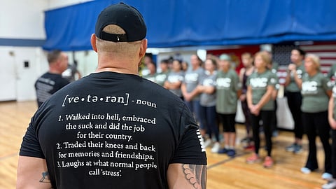 veterans stand in front of a group of people in a group exercise class in a gym