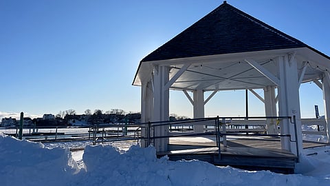 white gazebo against the sunrise and piles of snow