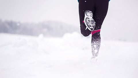 white powder snow with a pair of legs wearing sneakers and black running tights running