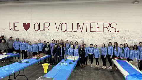 a group of people in a warehouse to package meals 