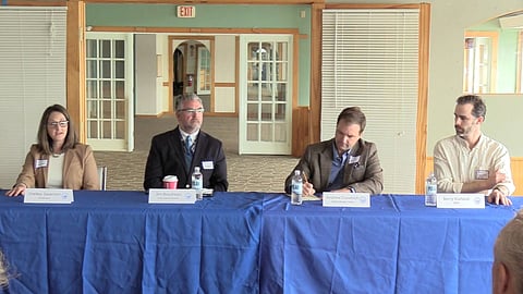 4 people sit at a table in a conference room 