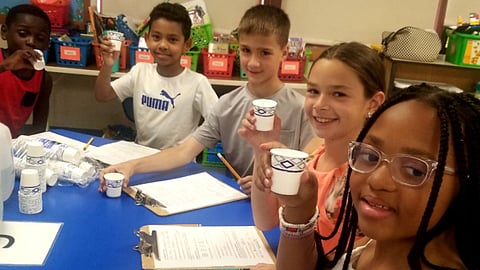 elementary school students experiment with water at a school science project