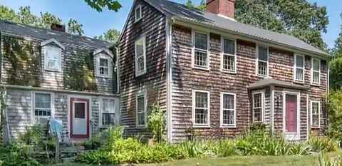 image of an old wooden house with grass and bushes around