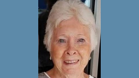 Close up phot of an older white woman with white hair smiling warmly 