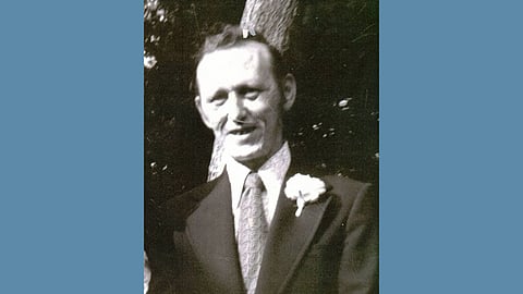 Vintage photo of a middle aged white man wearing a tuxedo or sport coat with a tie and flower on the lapel 