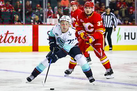 Seattle Kraken center Berkly Catton (77) controls the puck against the Calgary Flames
