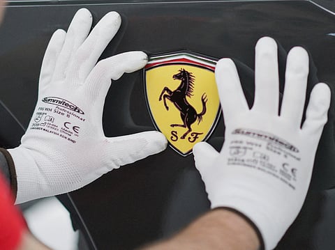 A Ferrari logo is being installed on a Ferrari car at Ferrari's new 'e-building' facility