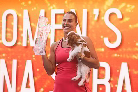 Aryna Sabalenka poses with the trophy and her dog 'Ash'