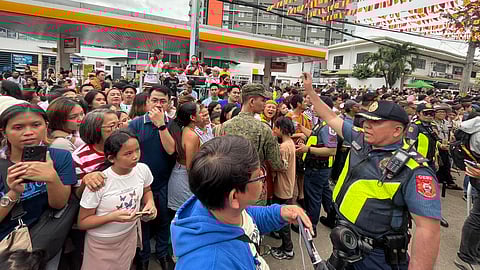 IMPOSING ORDER. Police officers tell the crowd to move back to ensure they do not block the contingents’ street dancing performance along Osmeña Blvd. in Cebu City during the Sinulog sa Lalawigan on January 14, 2024.  