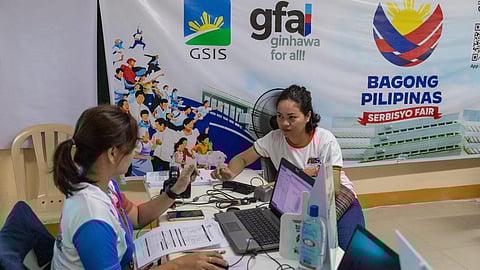 MOBILE APP. The Government Service Insurance System (GSIS) promotes the application for the Multipurpose Loan (MPL) Flex through the GSIS Touch mobile app during the Bagong Pilipinas Serbisyo Fair. The photo shows a GSIS Naga Branch Office staff member attending to a client at the Camarines Sur fair in September 2023. 