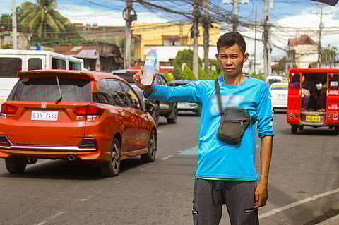 PALAMIG KA MUNA. A man selling water on a hot day to the passing vehicles along Quezon Boulevard in Davao City. After continuous rains, the city is again experiencing intermittent hot, sunny days.