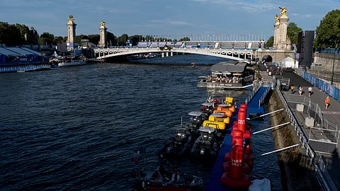 Watercraft and buoys sit along the Seine River as the triathlon event venue on the Pont Alexandre III bridge stands in the background at the 2024 Summer Olympics, Sunday, July 28, 2024, in Paris. (AP)