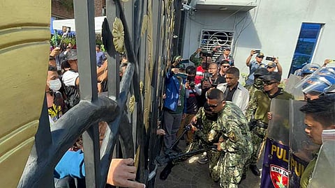 STANDOFF. Police personnel are seen forcing entry at the Emerald Gate of the Kingdom of Jesus Christ (KOJC) compound, despite another gate being open for access. 