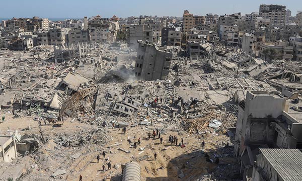 Palestinians walk through the destruction left by the Israeli air and ground offensive on the Gaza Strip near Shifa Hospital in Gaza City, on April 1, 2024.