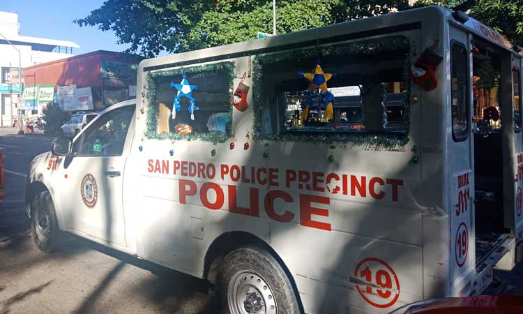 In this file photo, a mobile police car parked in front of the San Pedro police station was spotted to have Christmas decorations all over but with the tarpaulin of wanted individuals too. 