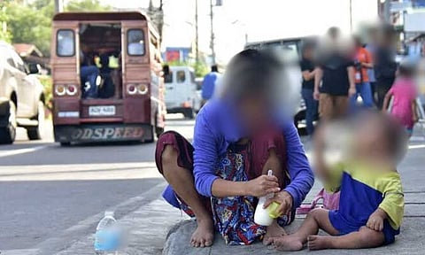 SIDEWALK FEEDING. A Badjao mother prepares a bottle of milk while her son bottle-feeds beside her at the sidewalk of Quezon Boulevard in Davao City just outside the evacuation area in Barangay 23-C Isla Verde.