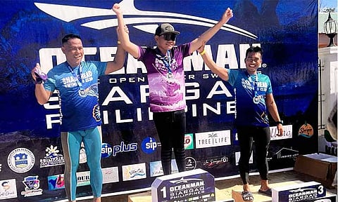 Palmer Taliño Taray, center, celebrates during the awarding ceremony of Oceanman Philippines.