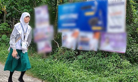 A young girl walks along Bacaca Road in Davao City, passing by a path lined with campaign posters. It's election season, and candidates are in full swing vying for public office. Filipinos will once again cast their votes on May 12, 2025.