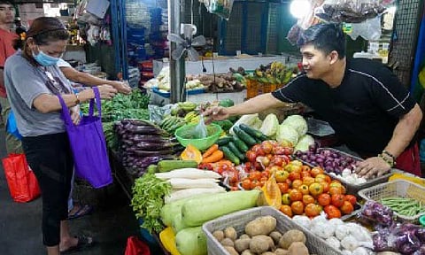 FRESH PICKS. A vendor hands a bag of vegetables to a customer at the Kamuning Public Market in Quezon City on May 27, 2025. The Department of Trade and Industry on Thursday (June 26, 2025) assured a steady supply of basic goods, saying that it is also actively working with manufacturers to keep prices reasonable. (PNA photo by Robert Oswald P. Alfiler)