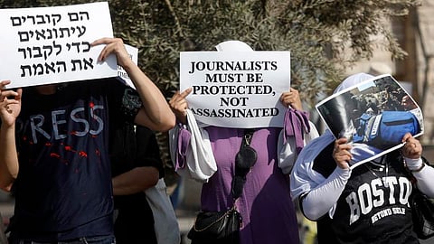 Palestinian and Israeli people hold placards and photos during a protest against Israeli army's killing of journalists, in the city of Beit Jala near Bethlehem, in southern West Bank, on August 15, 2025.