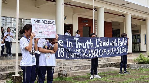 Students holding up signs and a banner during a campus rally against corruption.