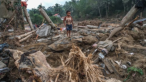 A child stands on a pile of debris from destroyed houses in the mountain barangay of Lusaran, Cebu City.