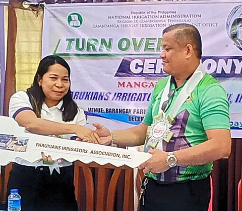 ZAMBOANGA. Ramces Enriquez, president of the Parukians Irrigators Association (right), formally accepts the Mangawil Pump Irrigation Project from Engineer Maria Gertrudes Gania, acting manager of the National Irrigation Administration–Zamboanga Sibugay Irrigation Management Office (left), during a turnover ceremony on Wednesday, December 10, at the Paruk village hall in Siay, Zamboanga Sibugay.