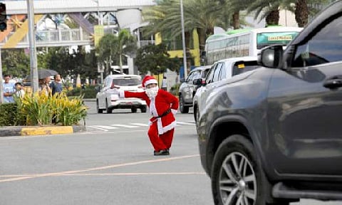 HOLIDAY MOOD. Traffic enforcer Ramiro Hinojas directs traffic while in Santa Claus costume along Macapagal Avenue in Pasay City on Tuesday (Dec. 23, 2025). Hinojas said has wears the costume during the Christmas season to lighten the mood of motorists caught in heavy traffic. (PNA photo by Yancy Lim)