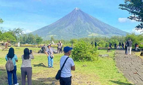 TOURIST DESTINATION. Tourists enjoy a clear view of Mayon Volcano from the Cagsawa Ruins in Daraga, Albay in this Feb. 1, 2025 photo. The Philippine Institute of Volcanology and Seismology raised the alert status of Mayon from Level 1 (low-level unrest) to Level 2 (increasing/moderate level of unrest) on Thursday (Jan. 1, 2026) due to a sharp increase in rockfall events and continued inflation of the volcano’s edifice. (PNA file photo by Connie Calipay)