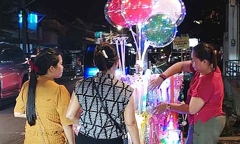 GLOW OF THE HOLIDAYS. A woman street vendor sells glowing balloons along Roxas Avenue in Davao City as tourists flock the nearby night market, hoping to earn extra income during the holiday season.